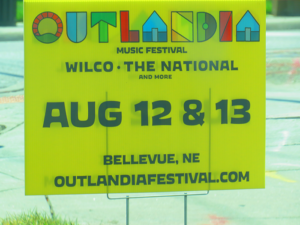 colorful Outlandia sign with text below 