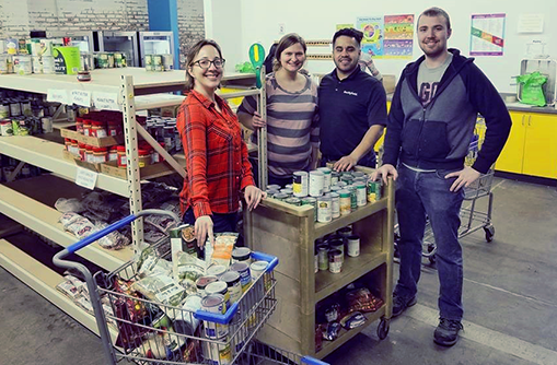 Four people smiling for picture with food in background